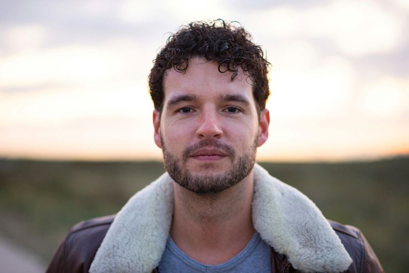 Aspiring male model posing outdoors for a portfolio photoshoot using natural light in the UK